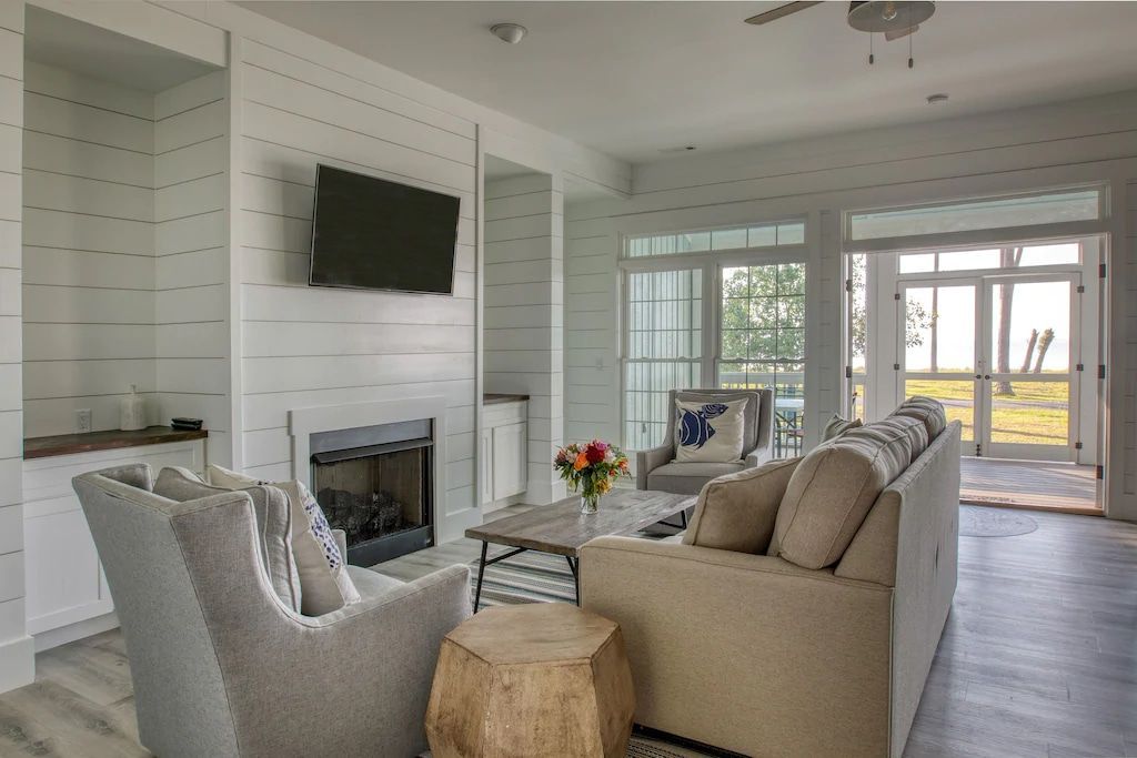 A living room with a couch , chairs , fireplace and television.