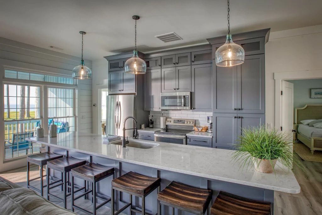 A kitchen with a large island and stools in a house.