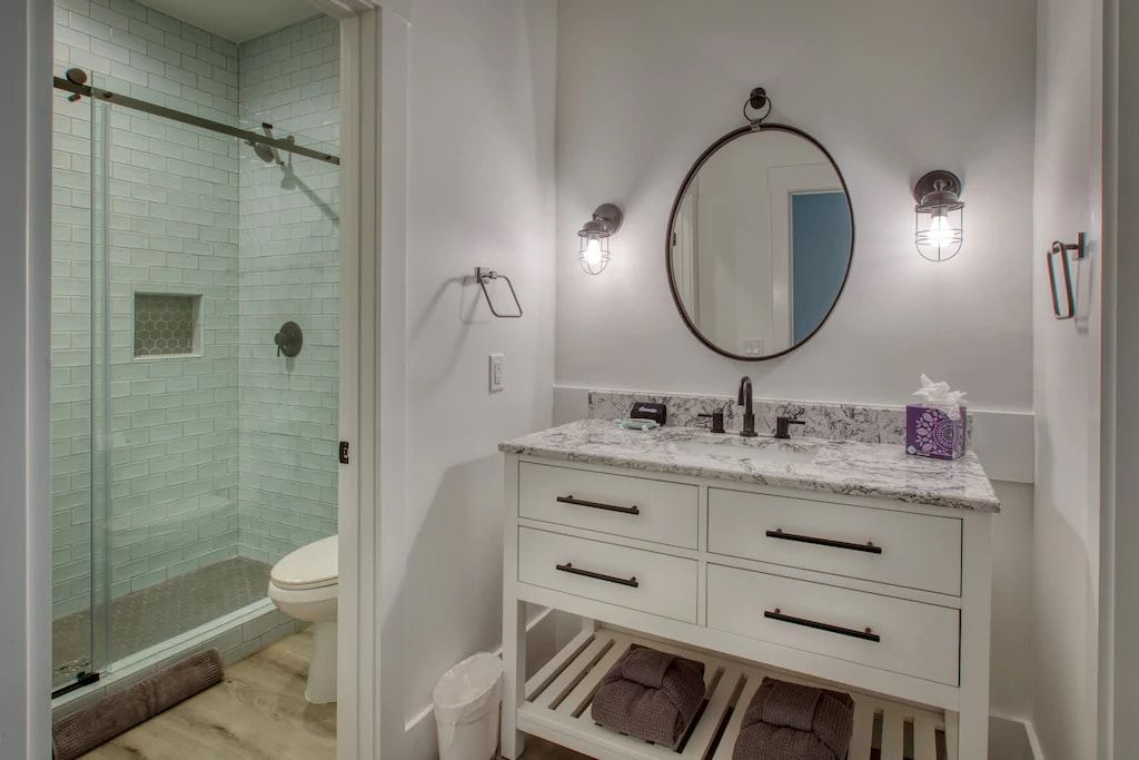 A bathroom with a sink , toilet , shower and mirror.