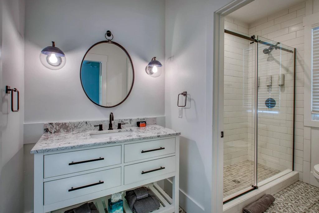 A bathroom with a sink , mirror and walk in shower.
