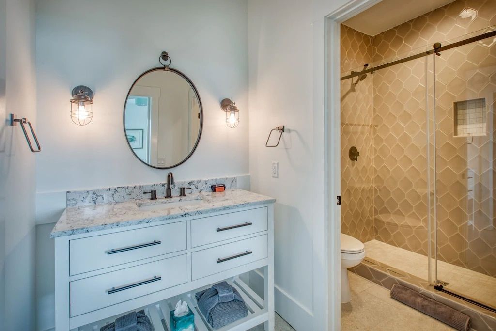 A bathroom with a sink , mirror , toilet and shower.