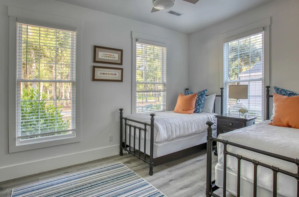 A bedroom with two beds , a rug , and a ceiling fan.