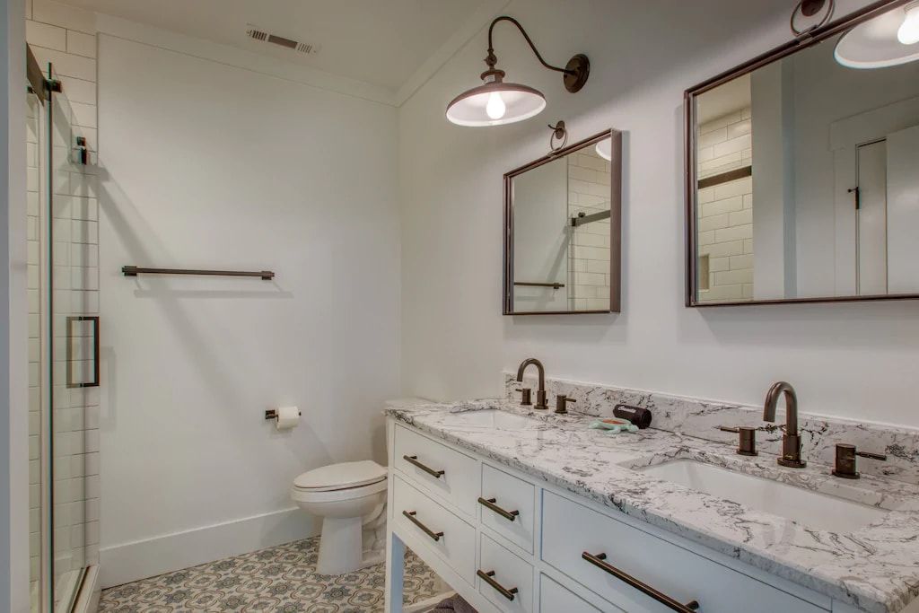 A bathroom with two sinks , a toilet , and a shower.