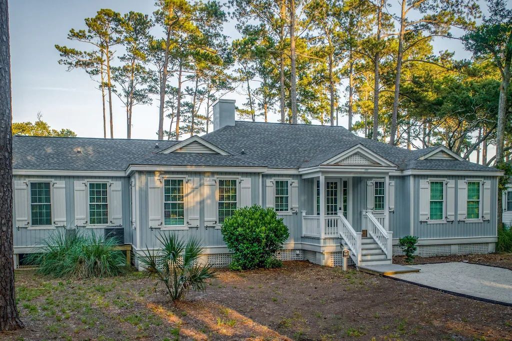 A house with a gray roof and white shutters is surrounded by trees.