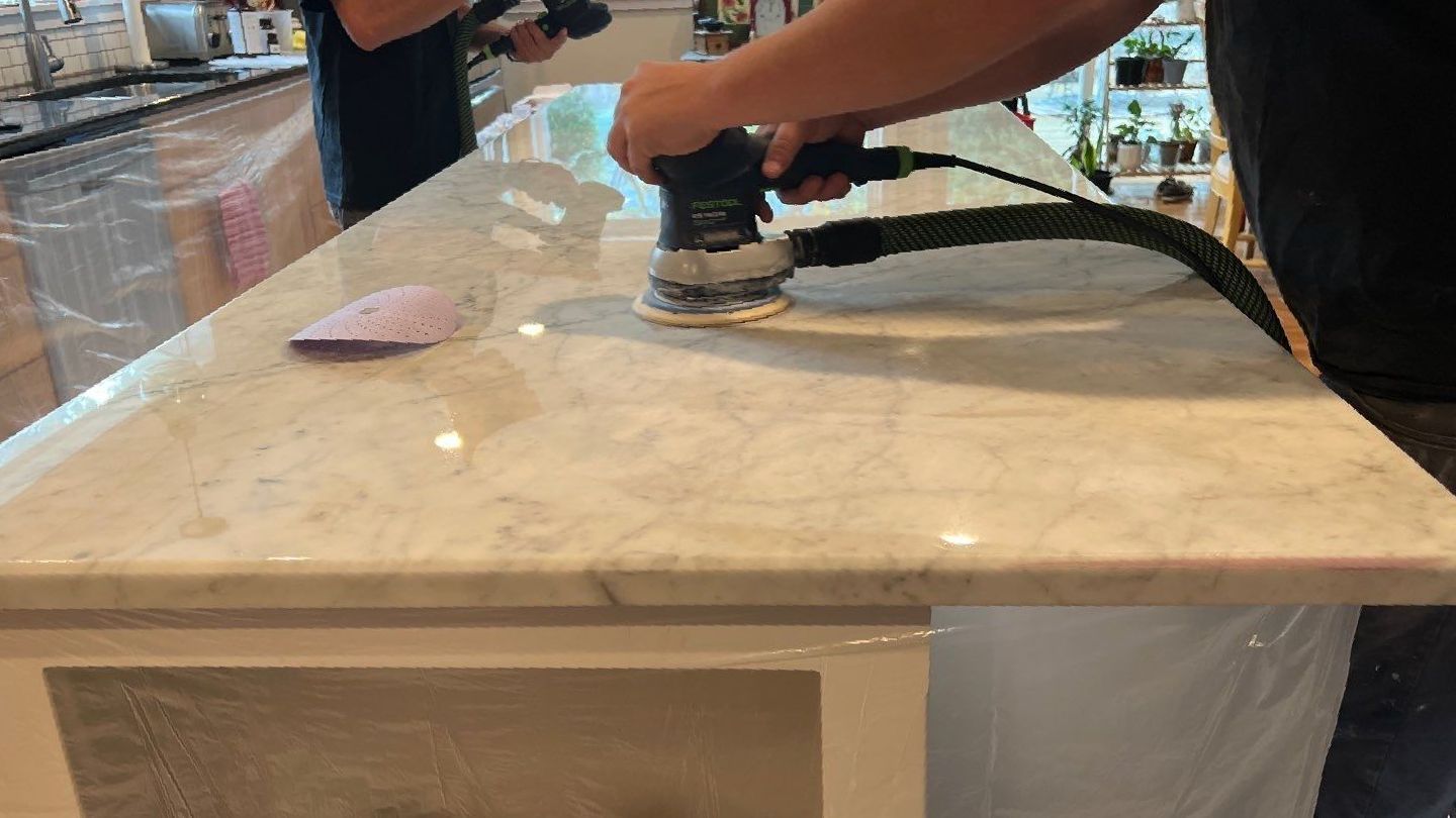 Polished white marble island countertop with gray veins, during a MORE® AntiEtch® treatment