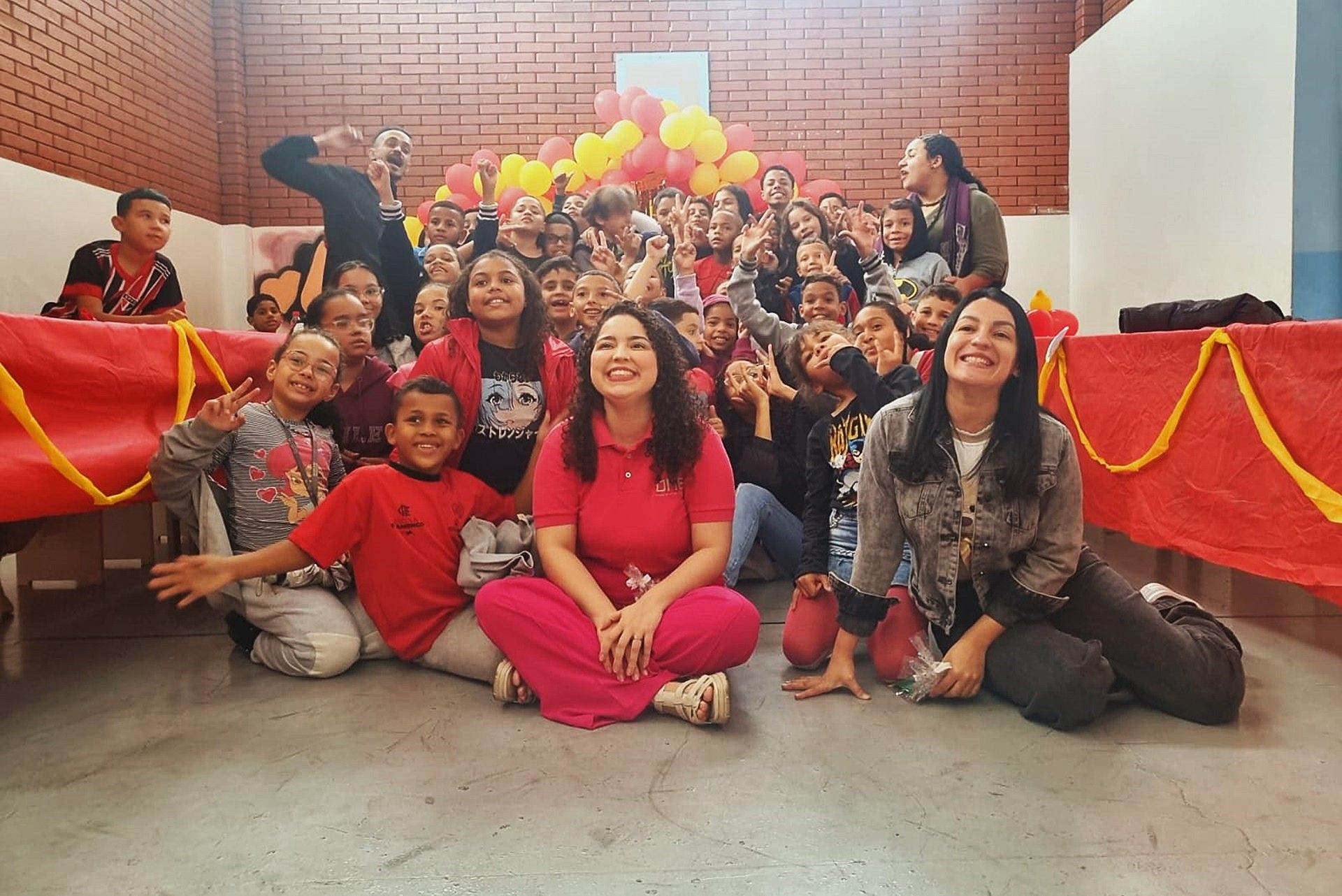 Um grupo de pessoas posando para uma foto, incluindo uma mulher com uma camisa rosa