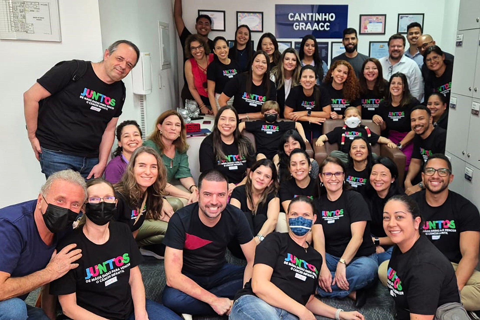 Um grupo de pessoas posando para uma foto em frente a uma placa que diz cantinho fraacco