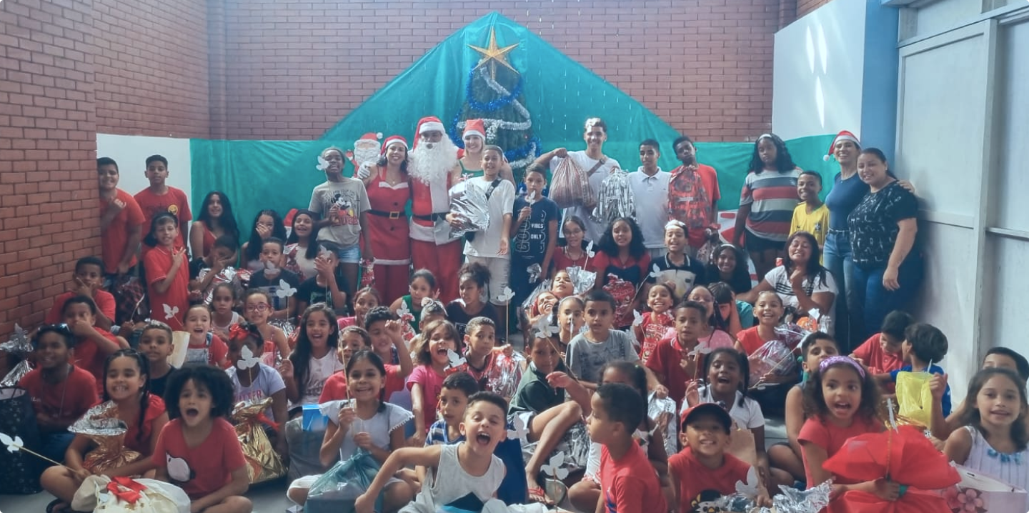 Um grupo de crianças está posando para uma foto em frente a uma árvore de natal