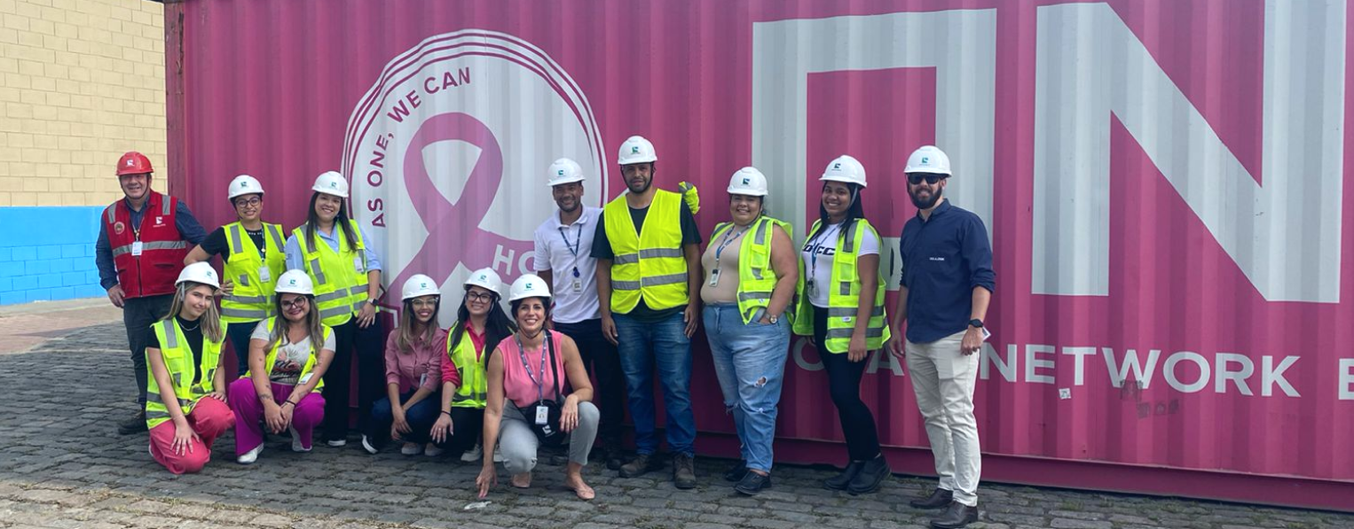 Um grupo de pessoas em pé na frente de um recipiente rosa que diz rede