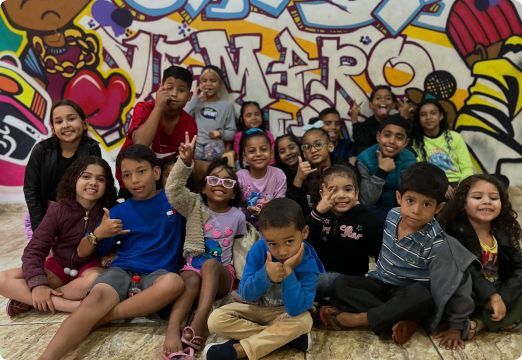 crianças Um grupo de crianças está posando para uma foto em frente a um muro de grafite.
