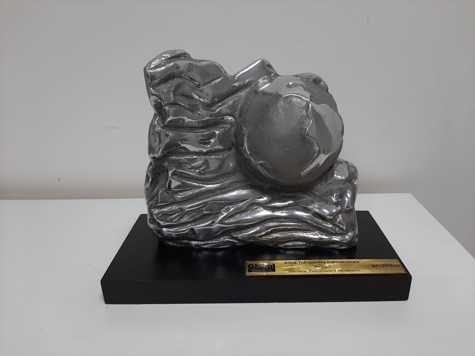 Uma estátua de prata sobre uma base preta com uma placa de ouro sobre ela