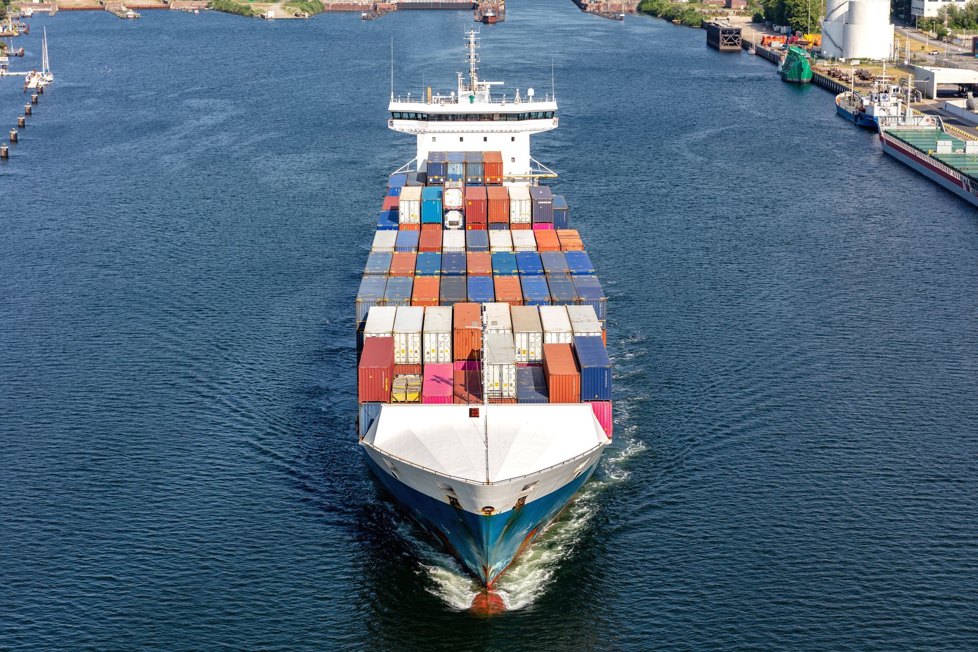 Uma vista aérea de um grande navio porta-contêineres flutuando sobre um corpo de água.