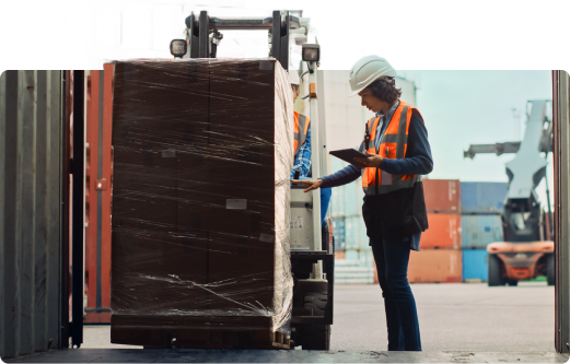 Uma mulher parada ao lado de uma empilhadeira olhando para um tablet