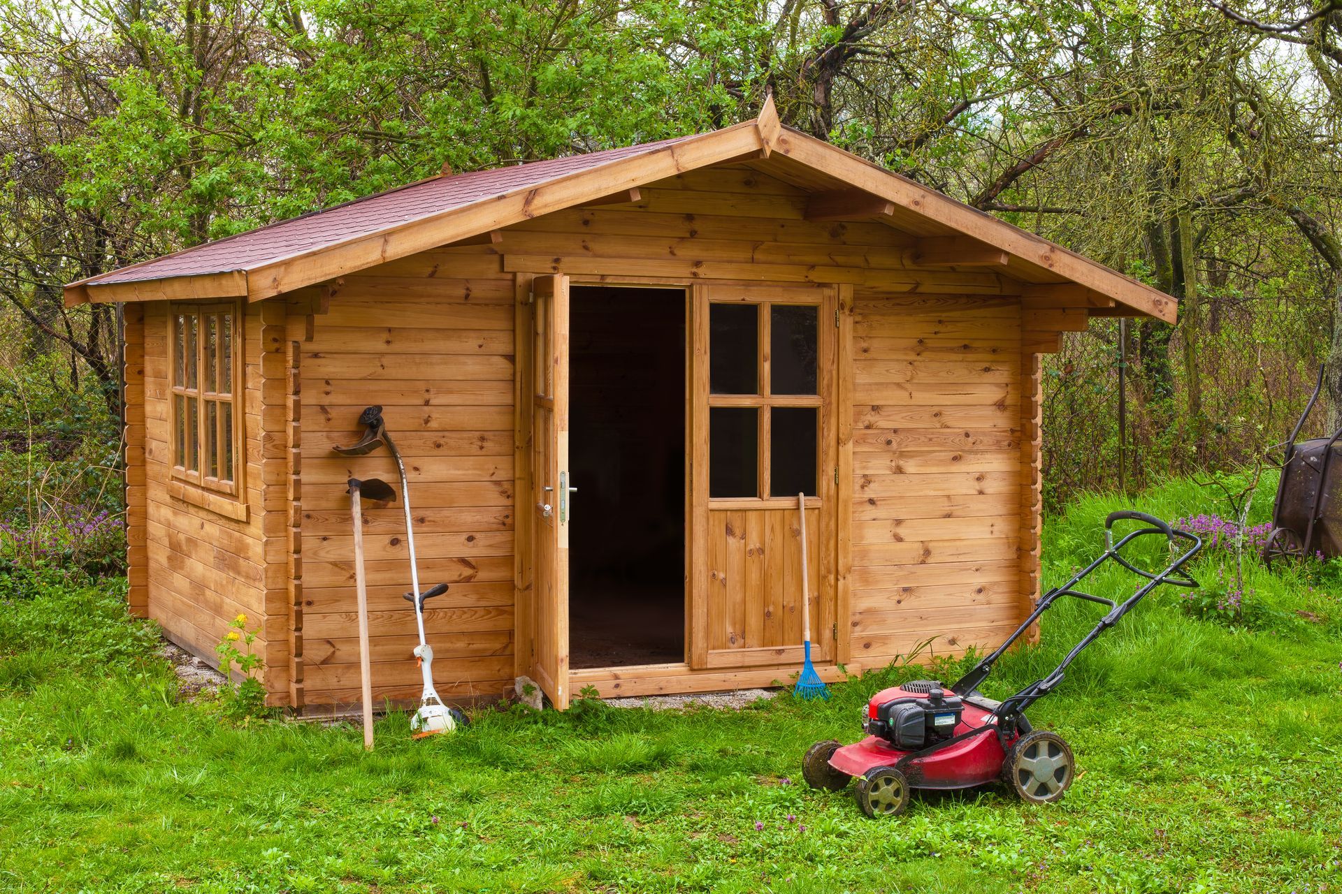 Garden shed with hoe, string trimmer, rake and grass-cutter.