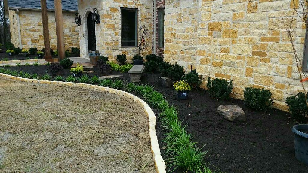 Stone house exterior with gravel path and dark mulch landscaping alongside a curved white border.