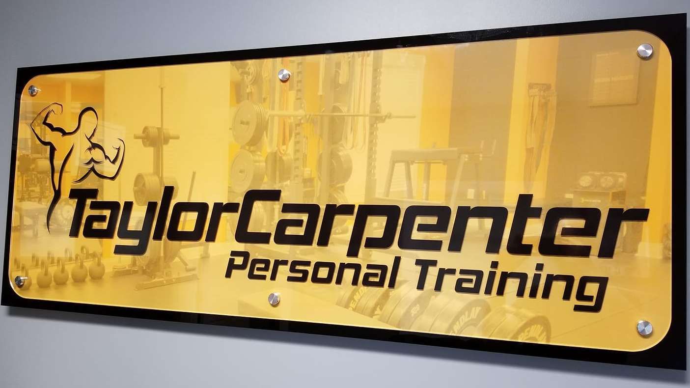 Yellow Taylor Carpenter Personal Training sign with black text and a flexing figure logo.