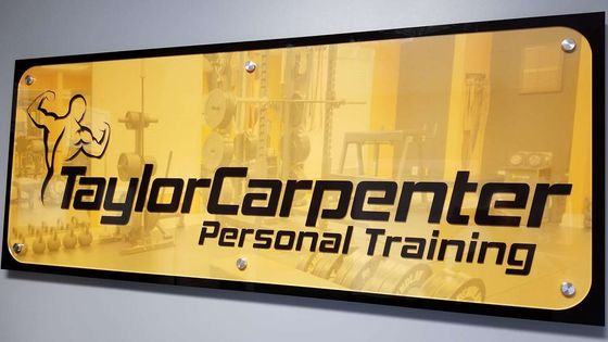 Yellow Taylor Carpenter Personal Training sign with black text and a flexing figure logo.