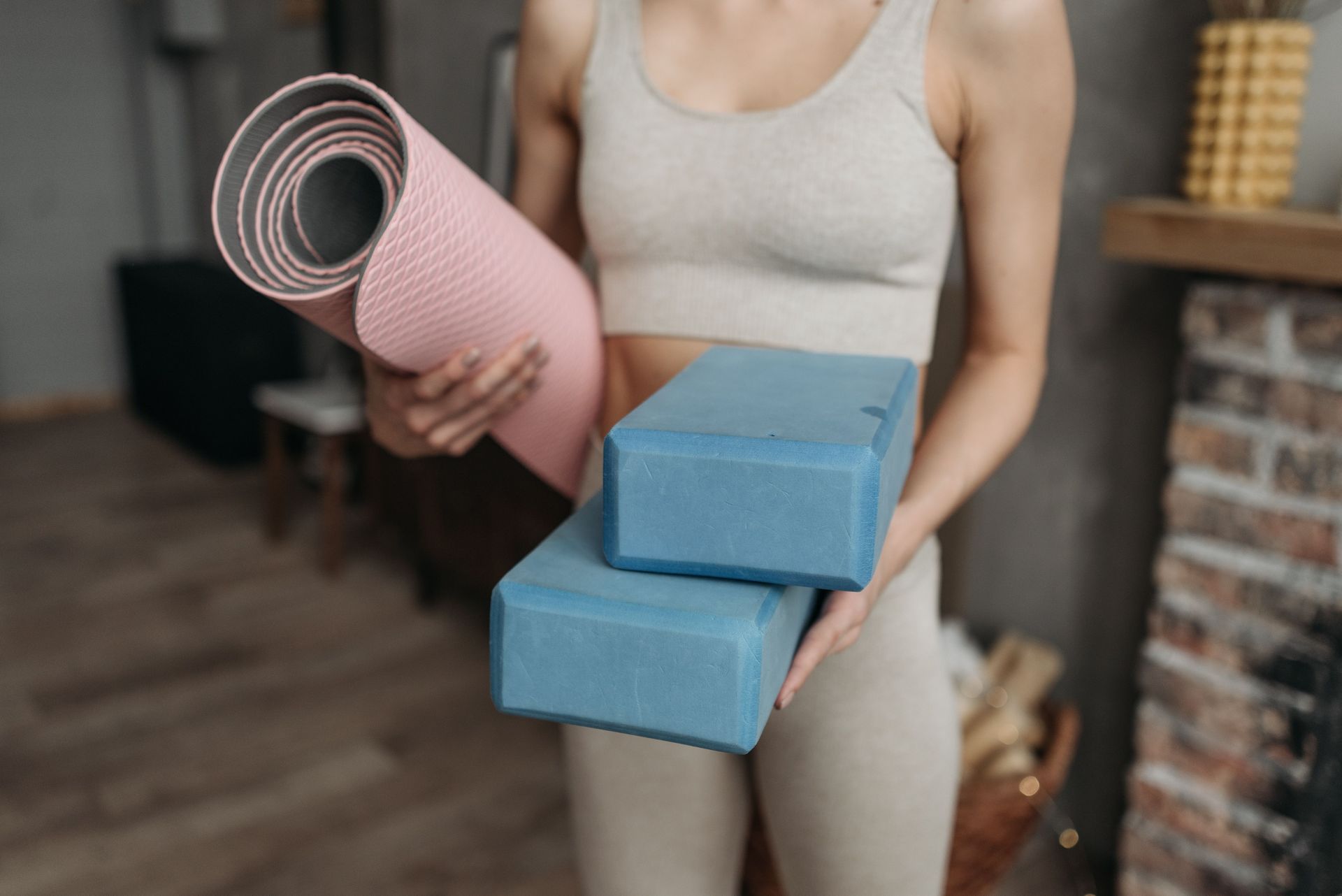 Personal trainer client holding a yoga block and yoga mat in a private fitness studio in Charlotte, NC