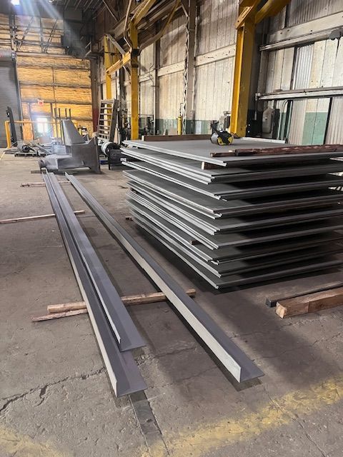 Metal sheets and beams stacked in an industrial workshop.