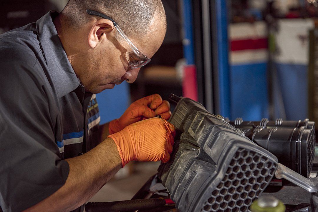 Mechanic wearing orange gloves inspecting a car engine in a workshop
