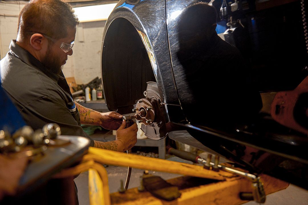 Worker using tools on a large black cylindrical machine in a workshop