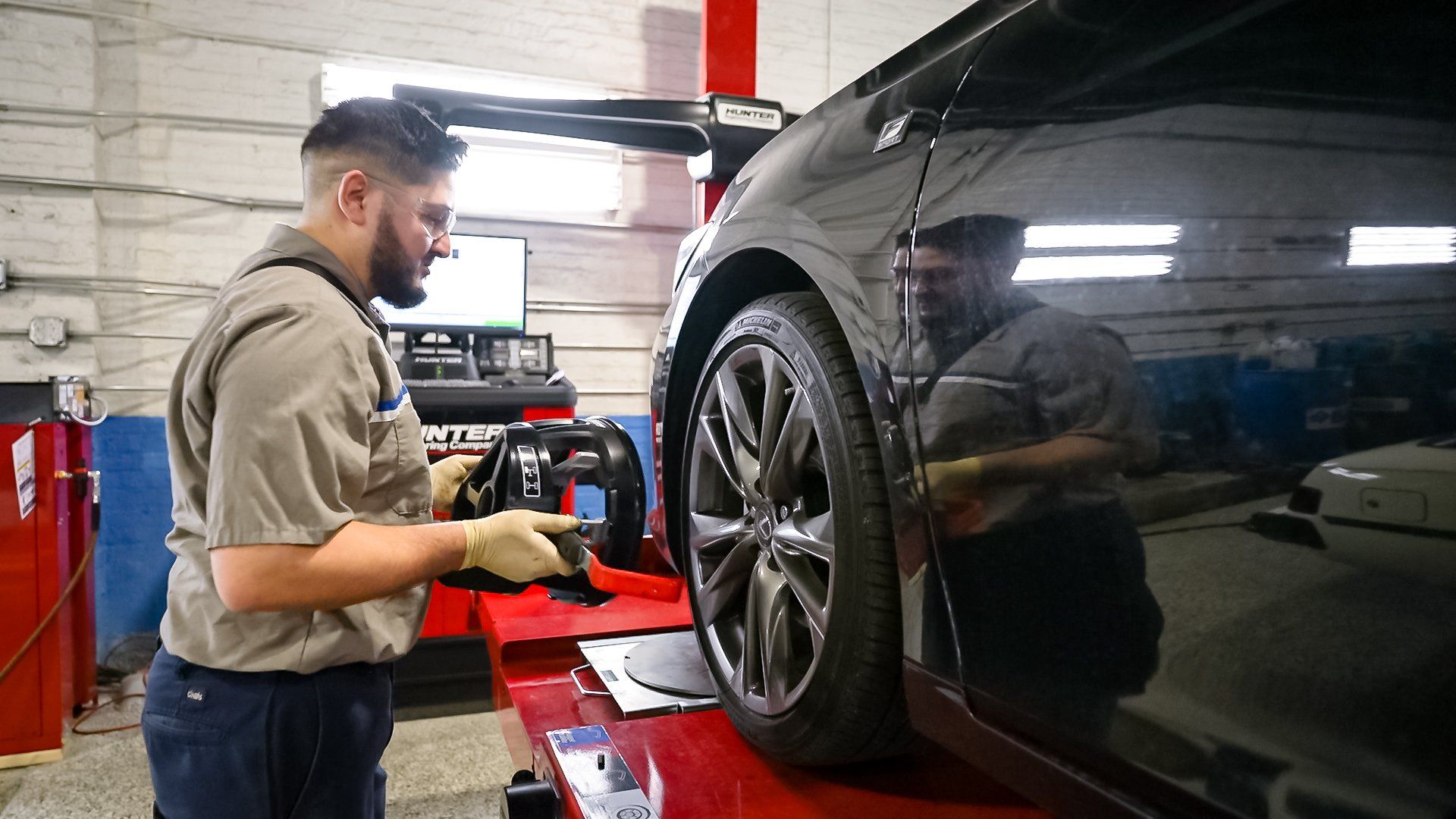 Mechanic inspecting a black car on a lift in an auto repair shop