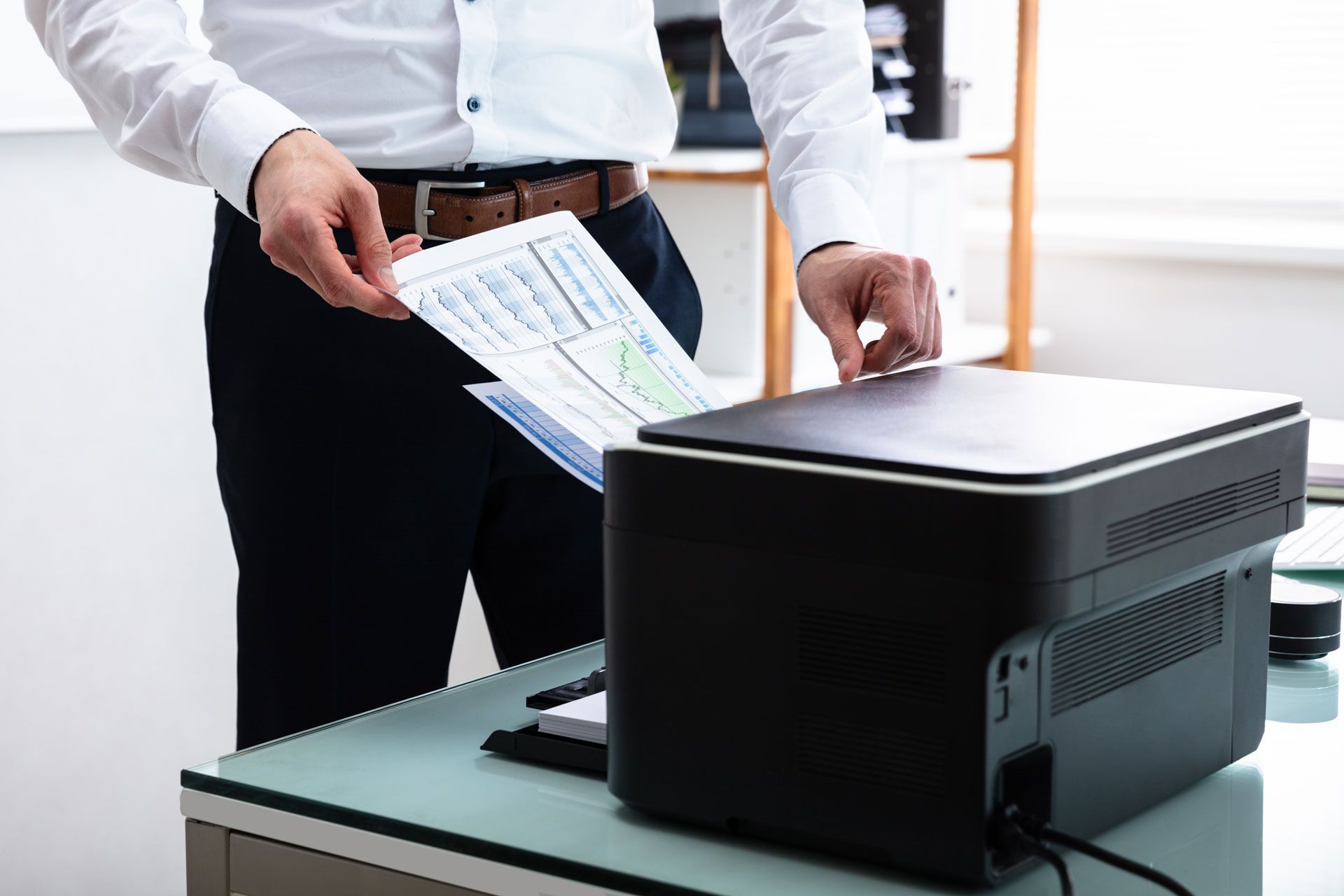 Person printing a document at a desk in an office setting.