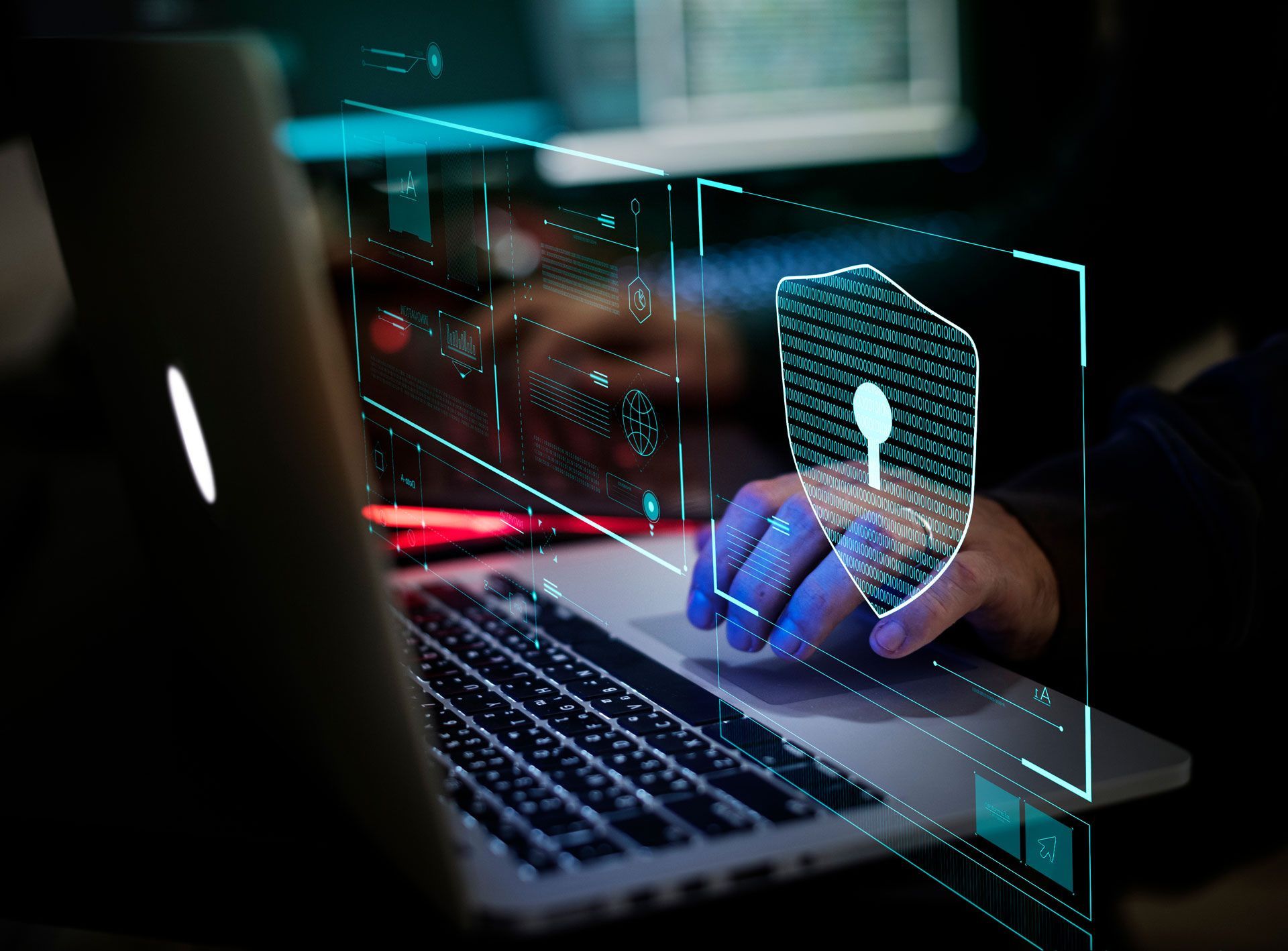 Person using a laptop with a digital security shield overlay; hands on keyboard, data visualization.