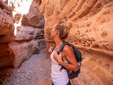 Woman with backpack exploring a narrow, sandstone canyon. Woman with backpack exploring a narrow, sandstone canyon.