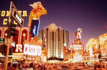 Neon cowboy sign on Fremont Street in Las Vegas, with casinos and street scene at dusk. Neon cowboy sign on Fremont Street in Las Vegas, with casinos and street scene at dusk.