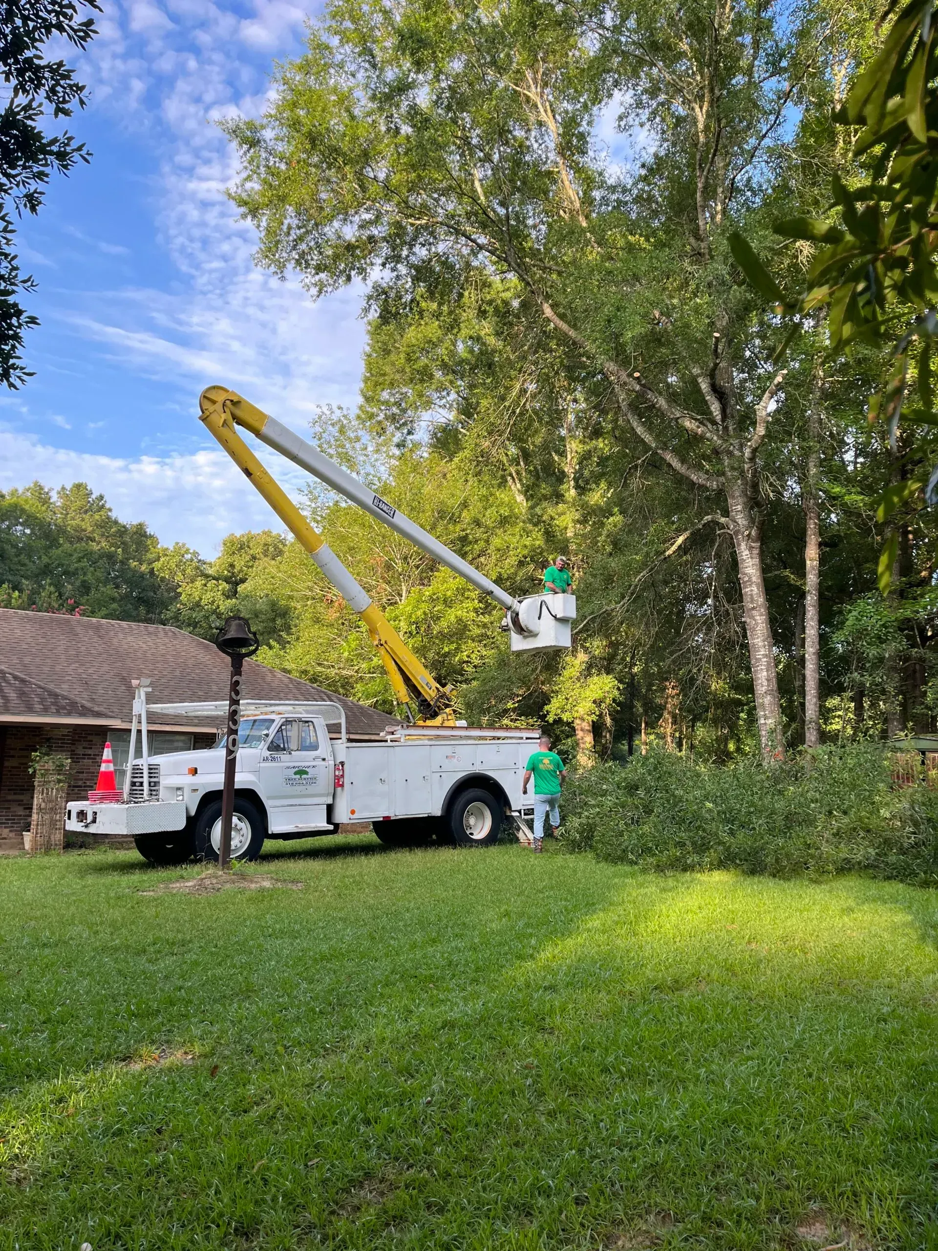 A white truck with a crane on top of it is parked in front of a house.