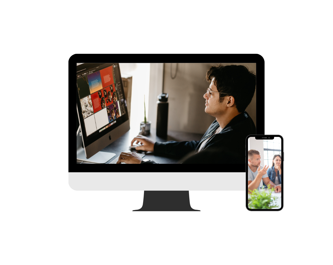 A man is sitting at a desk using a computer and a cell phone.