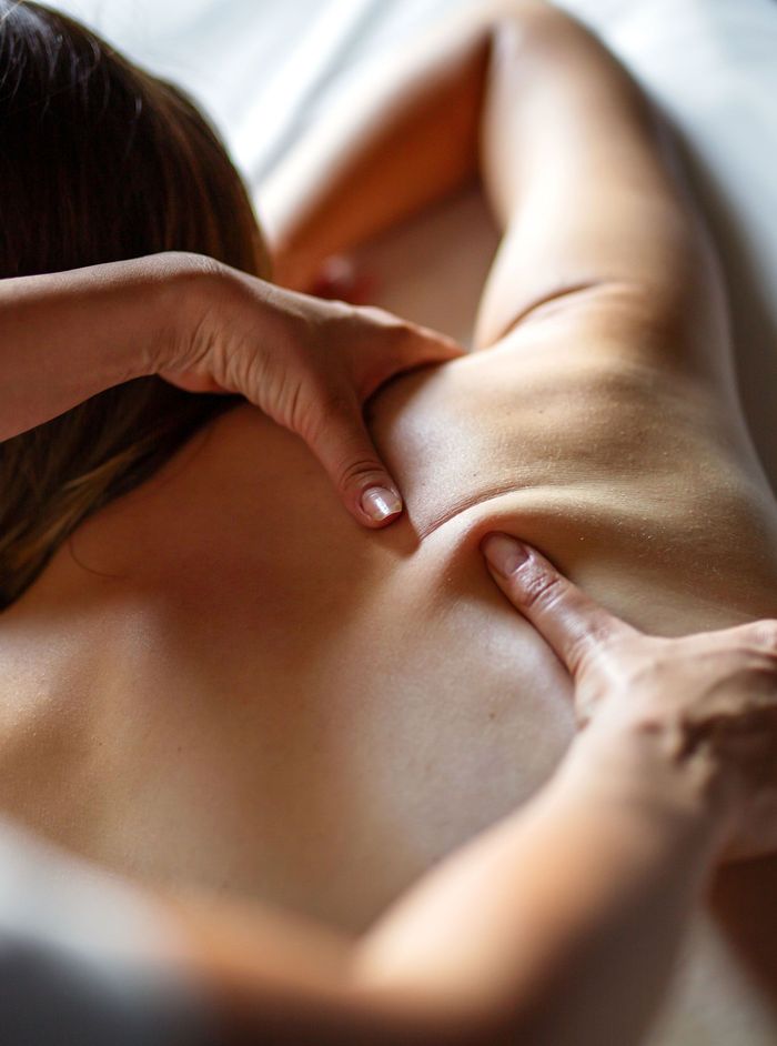 Hands massaging a person's upper back and shoulder.