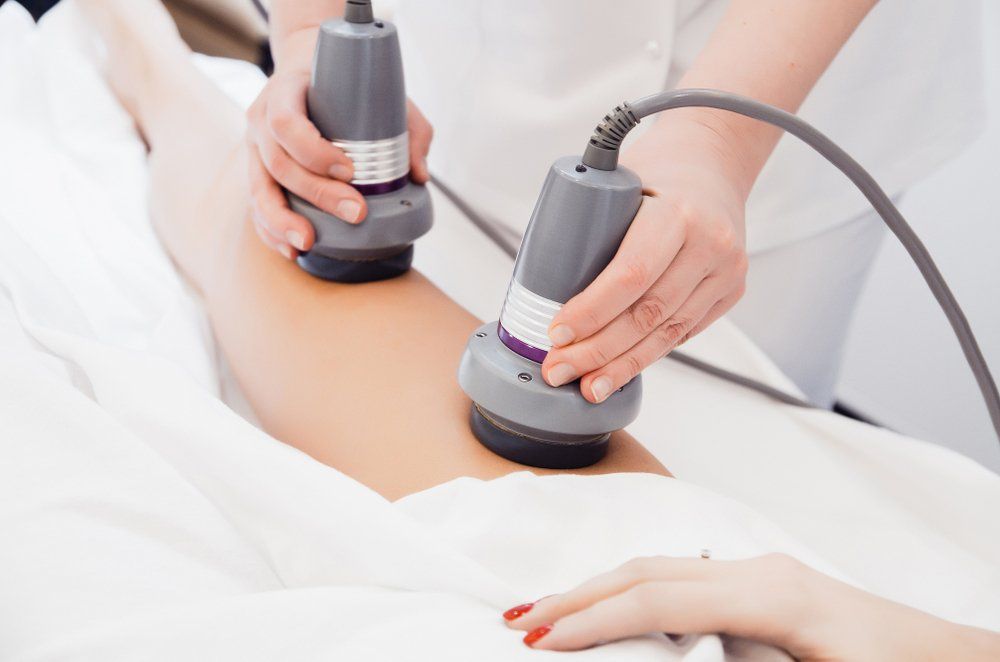 Therapist using ultrasound device on a person's leg during a spa treatment.