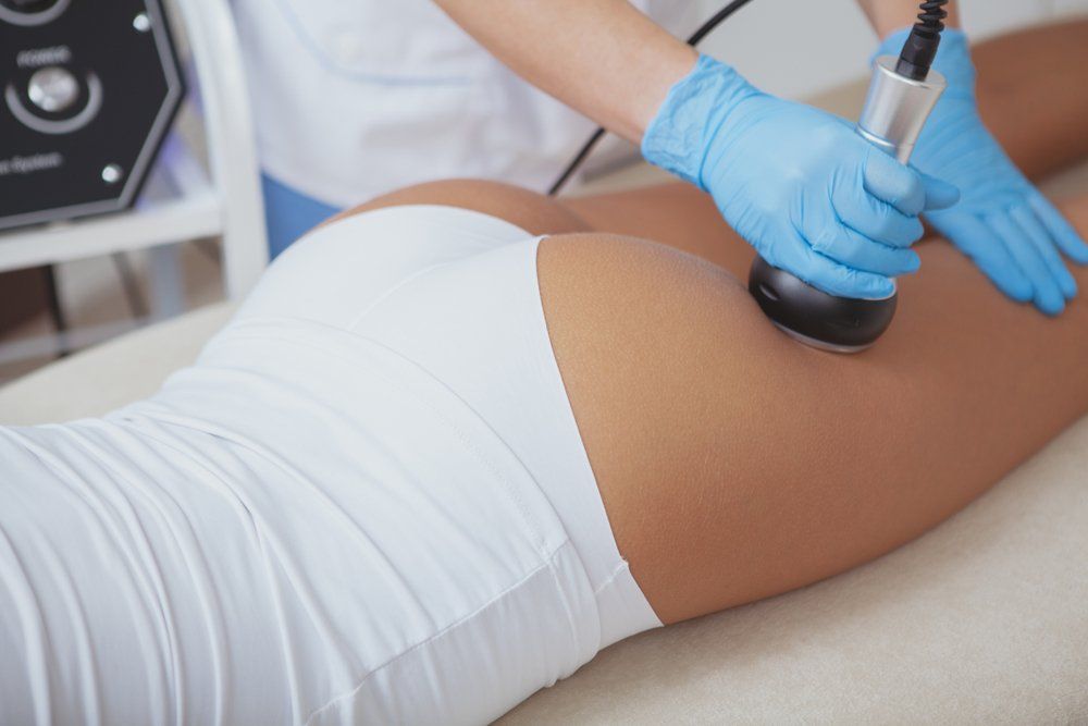Person receiving buttock treatment with a device, wearing white underwear, blue gloves.