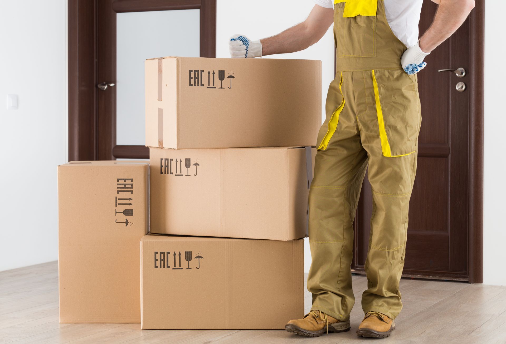 A storage mover stands next to a tower of boxes in front of an apartment. A storage mover stands next to a tower of boxes in front of an apartment.