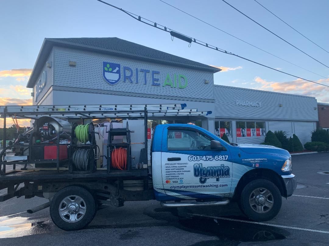 A service truck with equipment parked in front of a Rite Aid pharmacy building under a clear sky.