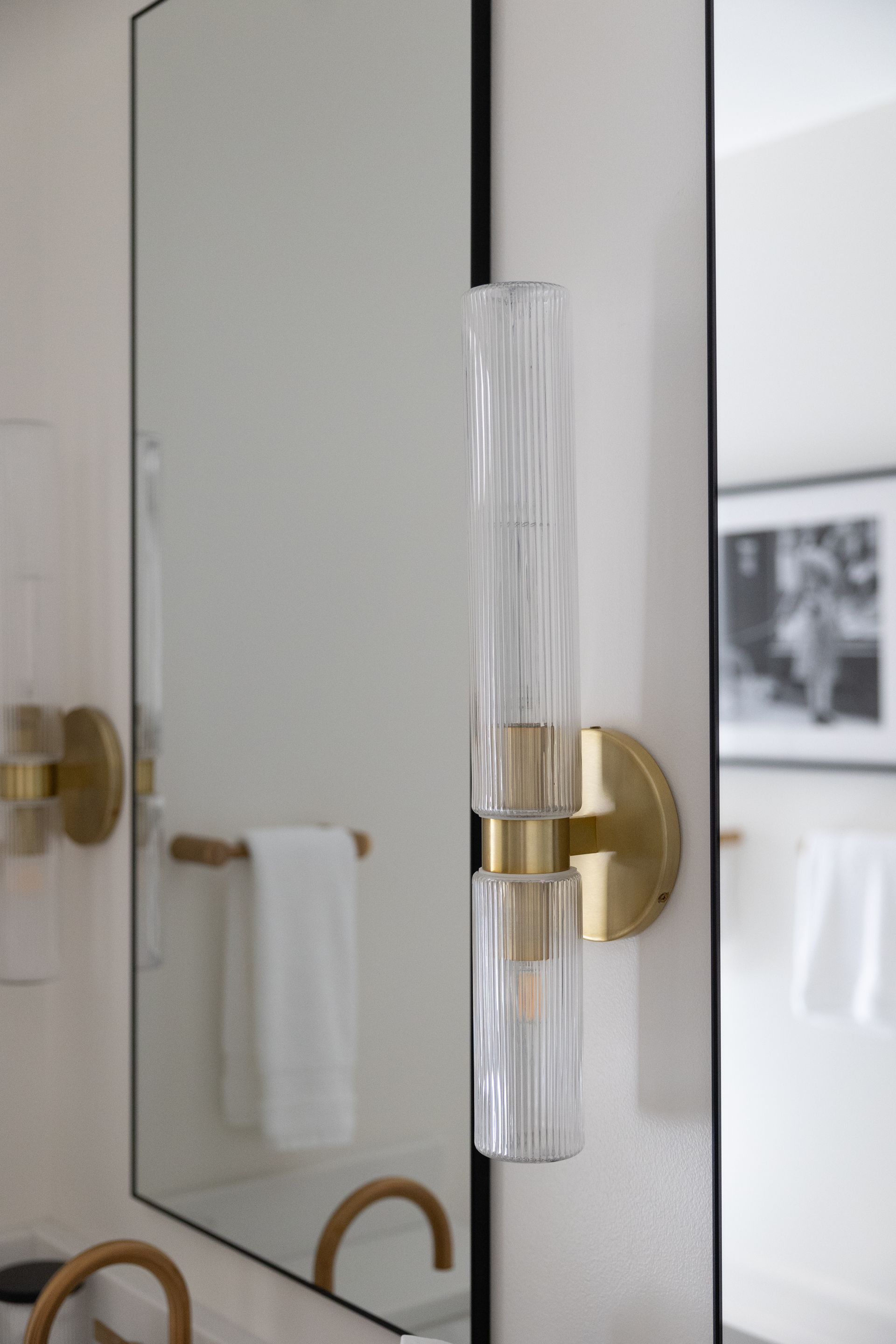 A bathroom with a large mirror and a light on the wall.