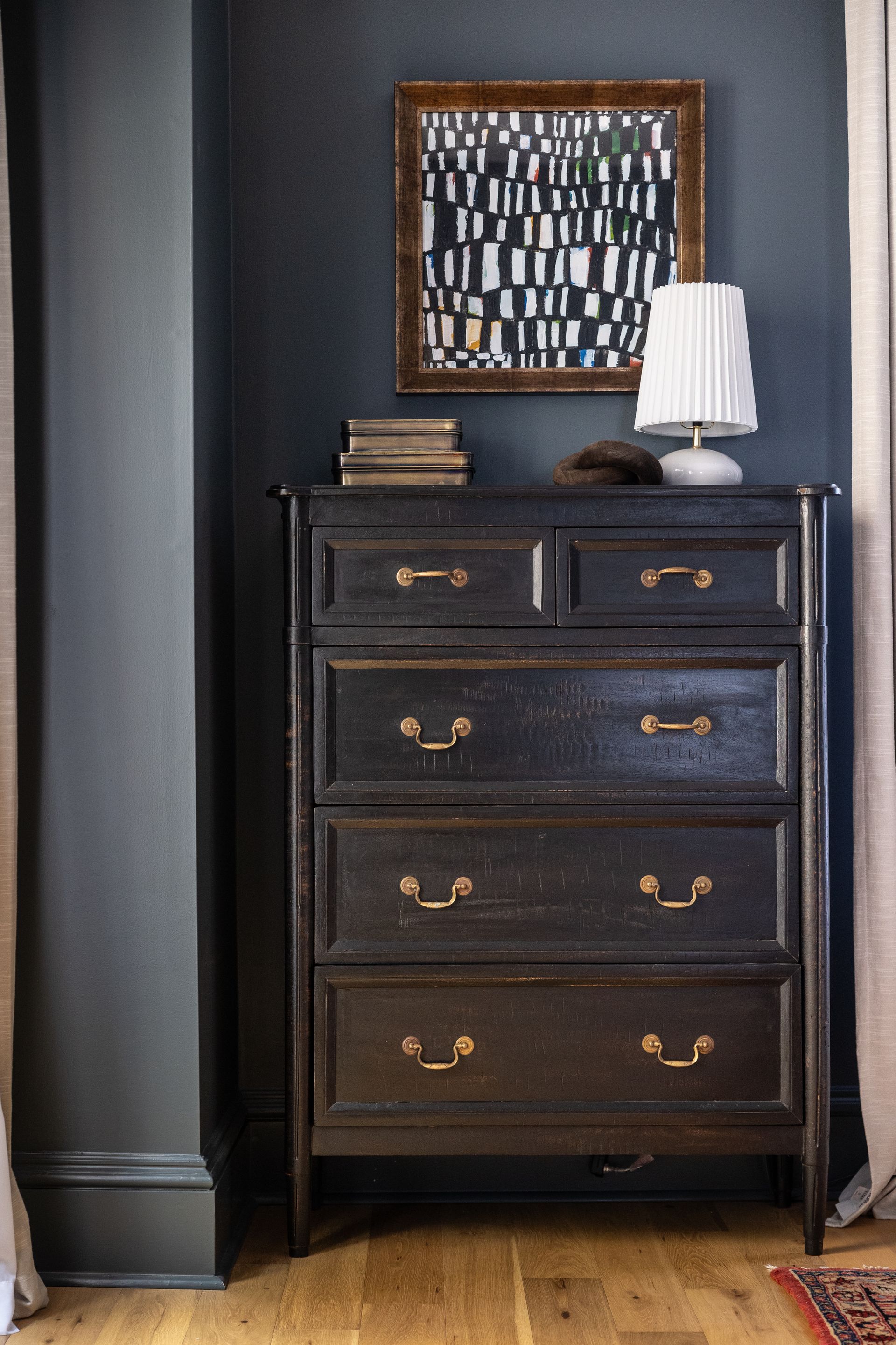 A chest of drawers in a room with a lamp on top of it.