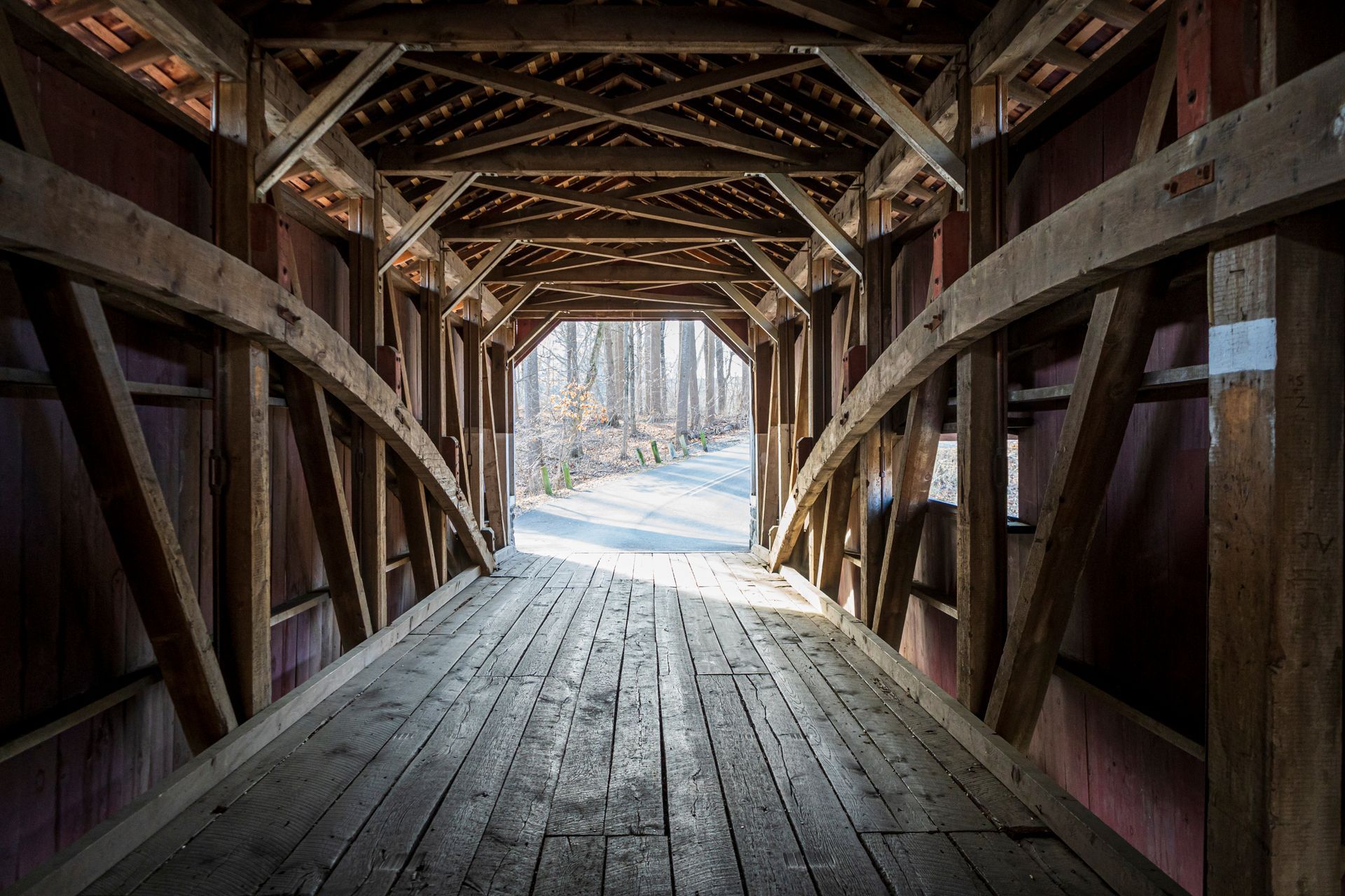 The inside of a wooden bridge with a wooden floor and a wooden roof.