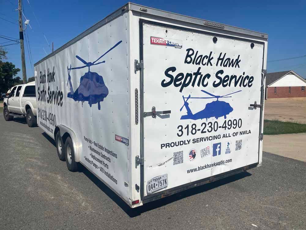 White trailer for Black Hawk Septic Service, parked on a street.  Phone number and logo on side.