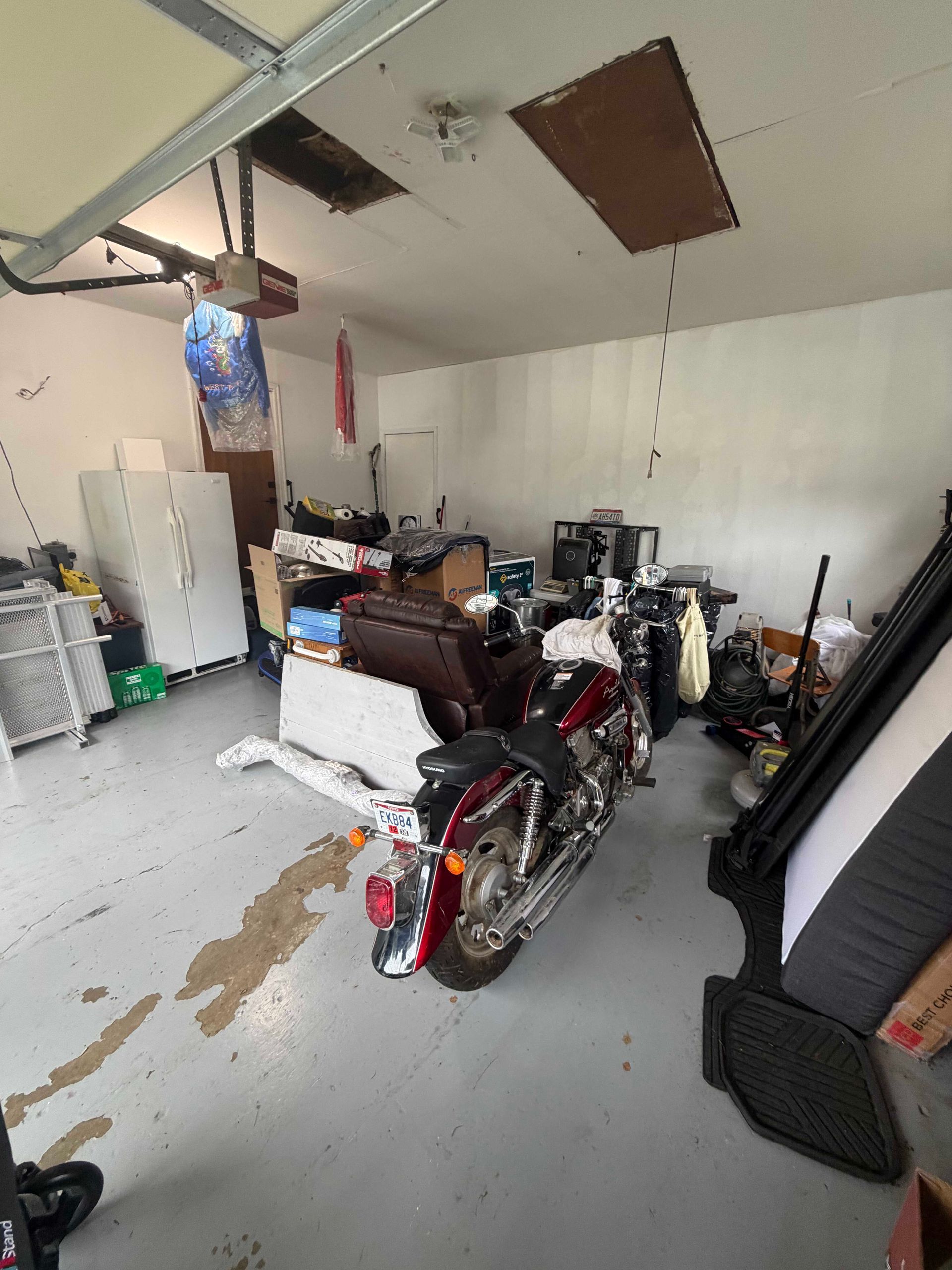 Garage with a motorcycle, storage items, and boxes on a concrete floor.