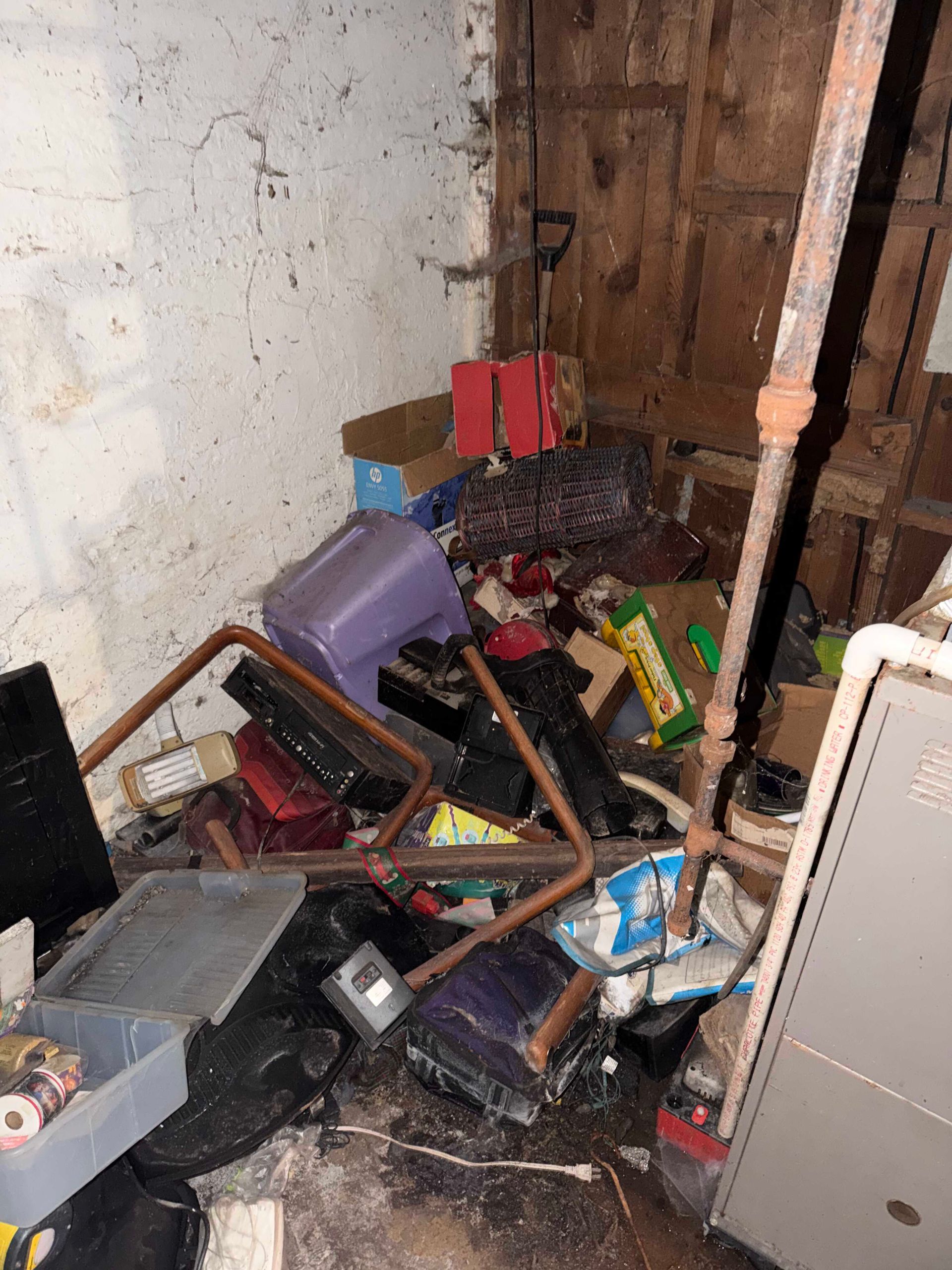 Cluttered corner with broken furniture, scattered debris, and peeling walls in a damaged room
