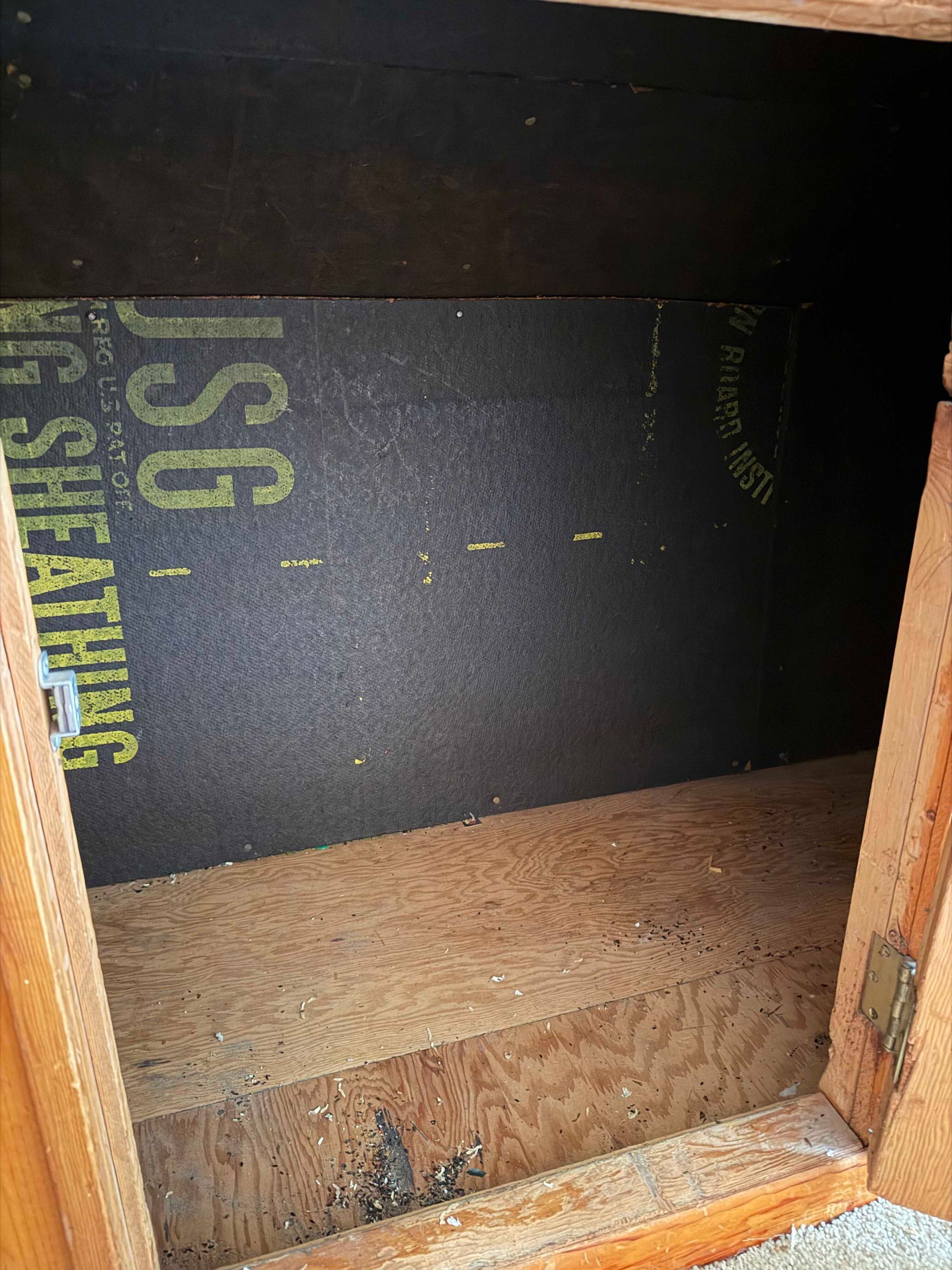 Empty wooden cabinet interior with black backing and a shelf, viewed from the front.
