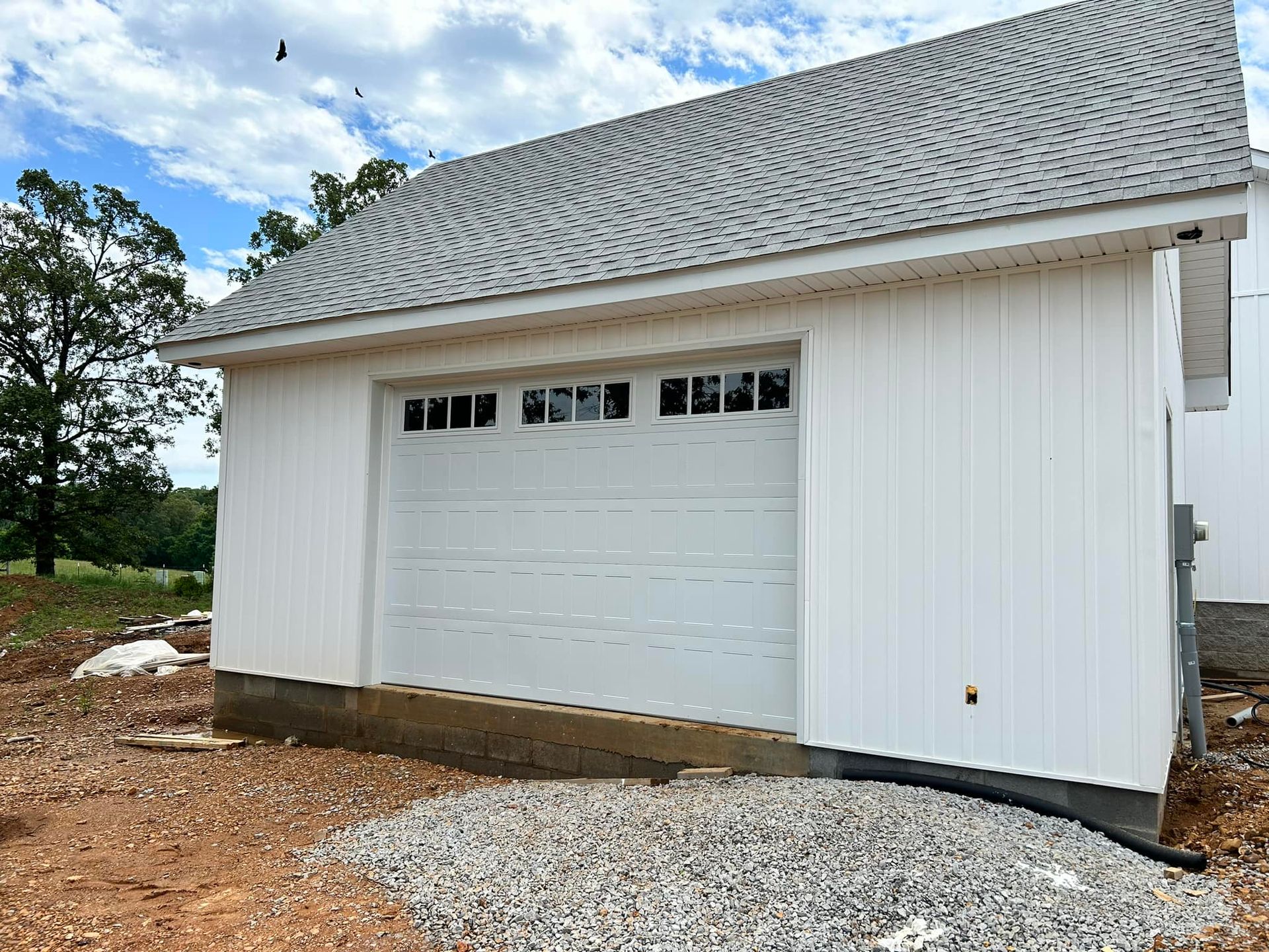 White garage with a gray roof and a row of windows above the closed garage door.