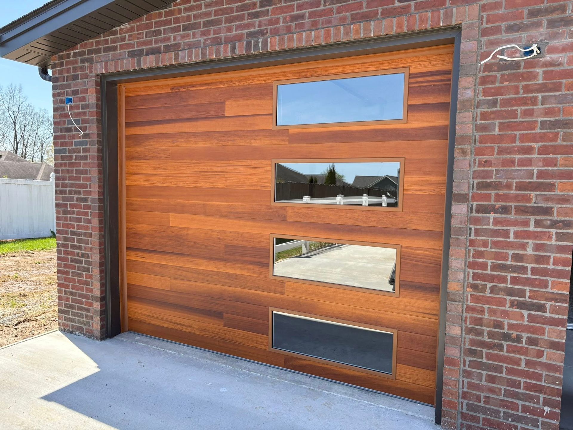 Wooden garage door with rectangular windows and a ventilation slot in a brick building.