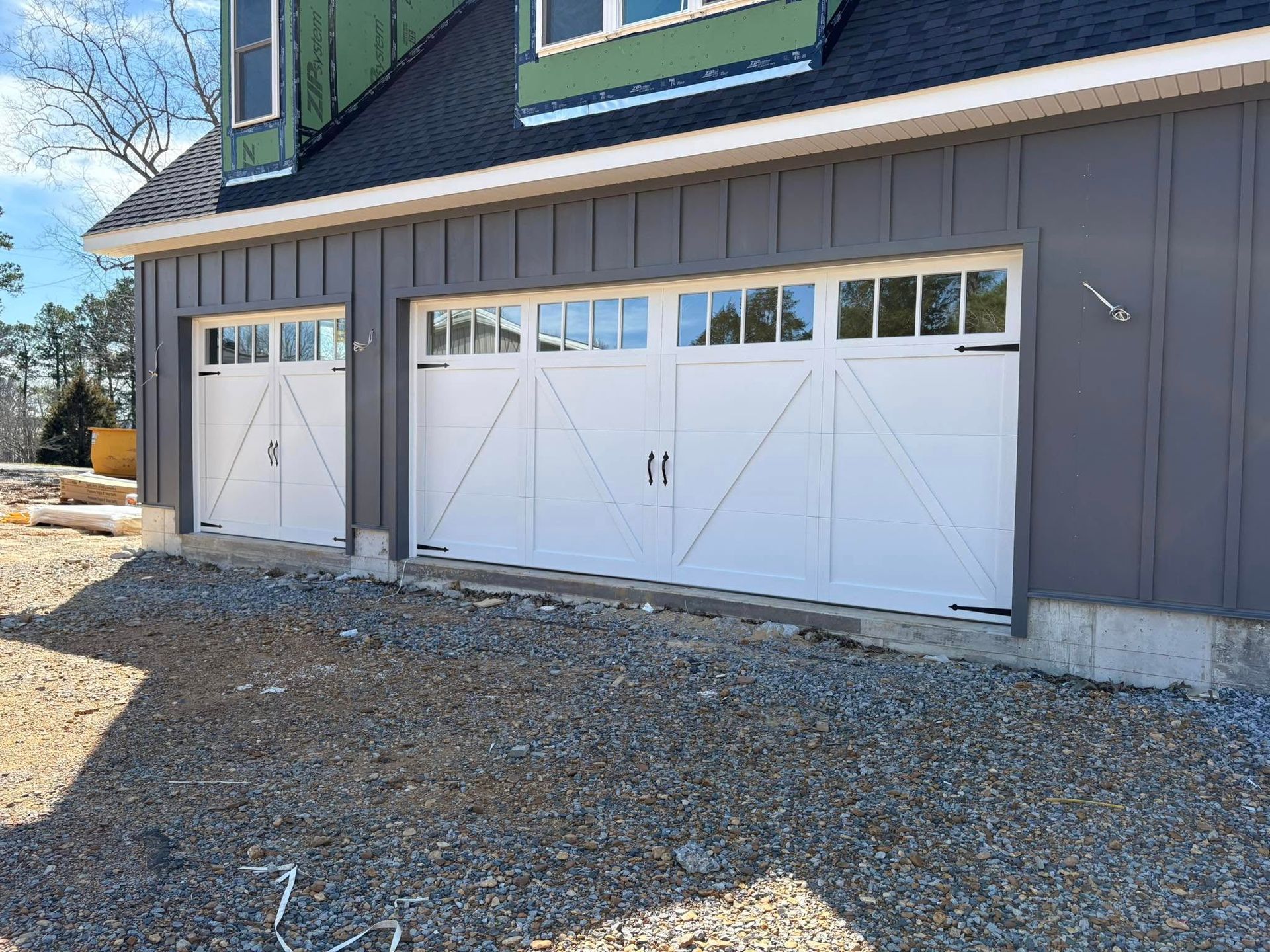 White garage doors on a gray house with matching siding.