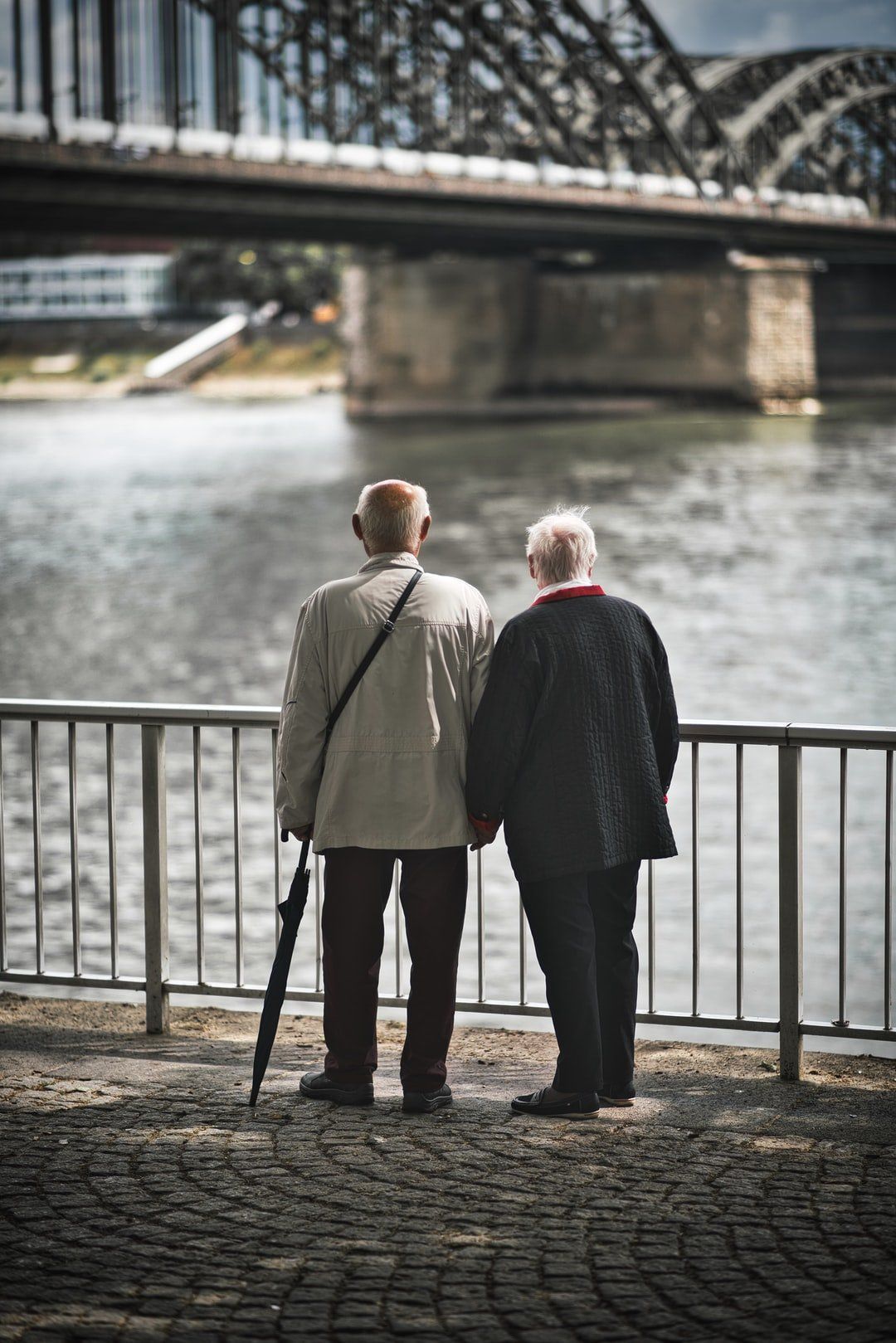 Two older men are standing next to each other looking at a river.