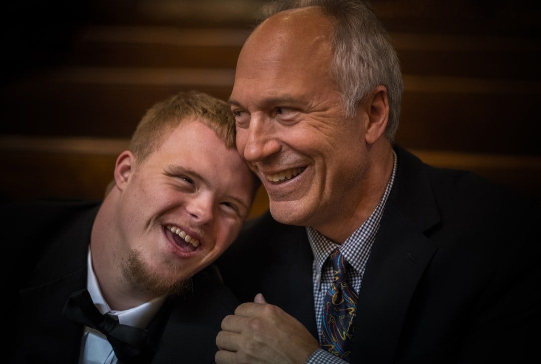 A man and a boy with down syndrome are smiling for the camera.