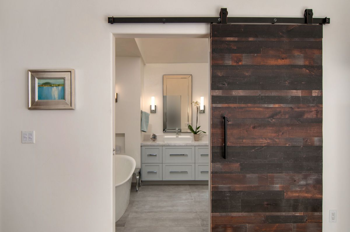 A bathroom with a sliding barn door leading to it.